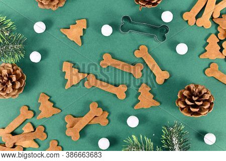 Top View Of Homemade Baked Dog Treat Cookies In Shape Of Bones And Christmas Tree On Festive Green B