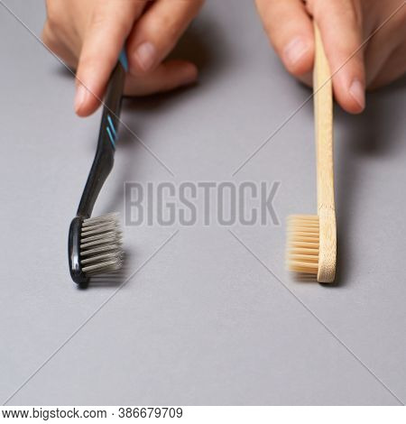 Two Hands Holding Different Types Of Toothbrushes. Plactic And Eco Bamboo Brush. Black And Light Col