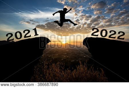 A Young Man Jump Between 2021 And 2022 Years Over The Sun And Through On The Gap Of Hill  Silhouette