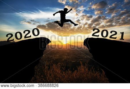 A Young Man Jump Between 2020 And 2021 Years Over The Sun And Through On The Gap Of Hill  Silhouette