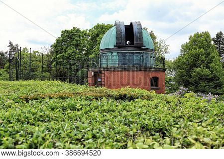 Open Cupola Of The Astronomy Observatory With The Telescope Lens Behind Hedge