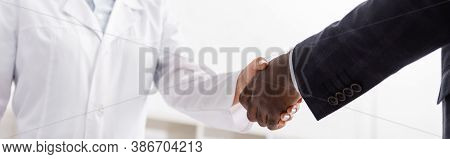 Partial View Of African American Man Shaking Hands With Doctor, Panoramic Shot