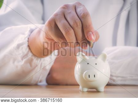 Closeup Of Senior Man Hand Putting Coin Into Piggy Bank To Saving Money For Retirement Financial And