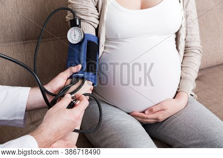 Young Doctor Is Checking Blood Pressure Of Pregnant Woman At Home. High Pressure Problem During Preg