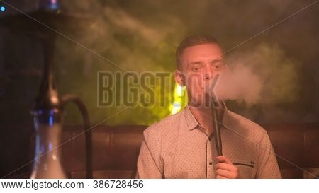 Young Blond Man Smoking Hookah And Producing Rings Of Smoke. Media. Magicical Smoking. Young Man Rel