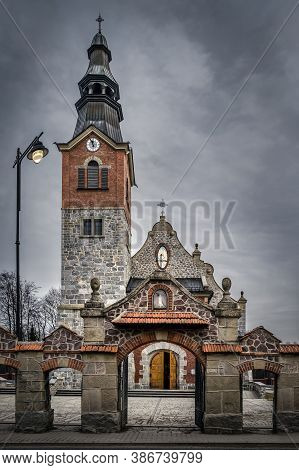 Old Stone And Brick Church With Clock Tower In Bialka Tatrzanska. Dark, Moody Storm Clouds And Drama