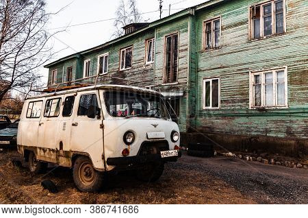 Petrozavodsk, Russia - 17 March 2020. Old Gray Uaz-452 Next To A Green Two-story Barracks
