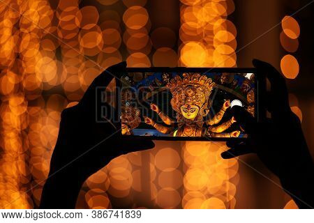 Hand Holding Mobile Phone And Taking Photos Of Goddess Durga Idol At A Pandal. Durga Puja Memories O