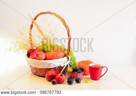 Orange Pumpkins, Grapes And Ginger Berries, A Red Mug With Juice, Pomegranate Fruits On A Table And 