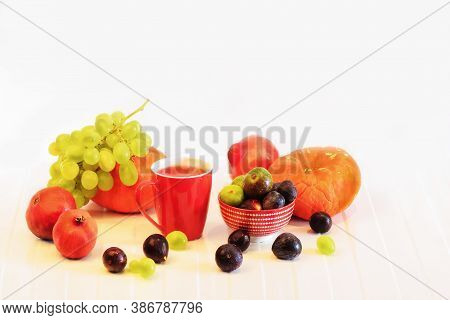 Orange Pumpkins, Berries Of Grapes And Ginger, A Red Mug With Juice,pomegranate Fruit On A White Bac
