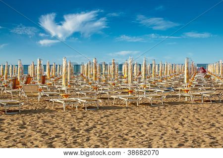 Sunlongers sulla spiaggia di sabbia e ombrelloni ritirati