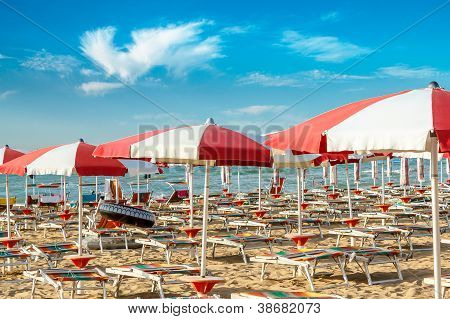 Roten und weißen Sonnenschirmen und Sunlongers auf den Sandstrand