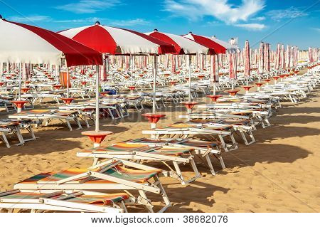 roten und weiÃŸen Sonnenschirmen und Sunlongers am Sandstrand