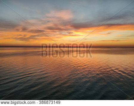 Beautiful Yellow Sunset On The Sea And Obloka On The Blue Sky, Reflected In The Sea Mirror.