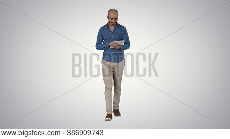Arabian Man Walking And Using Tablet Surfing Internet On Gradien