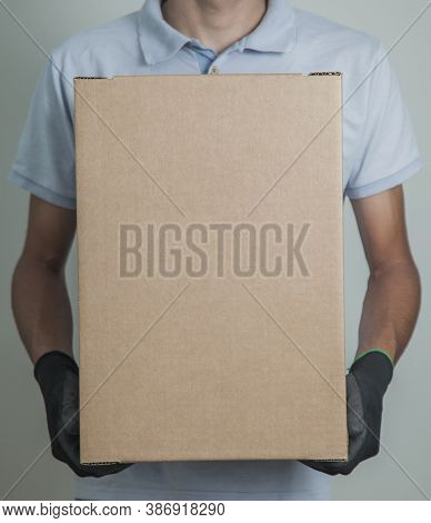 Detail Of Man With Black Gloves Holding A Cardboard Box For Delivering Products On Gray Background. 