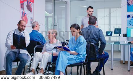 Doctor With Stethoscope Holding Disabled Senior Woman Radiography In Wheelchair While Talking With H