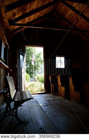 Light Streams Through The Doorway And Window Exposing Desks In A Rural One Room Schoolhouse. (black 