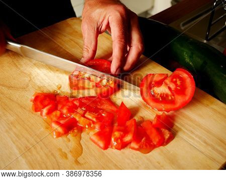 Man Cutting Tomatoes On A Wooden Board