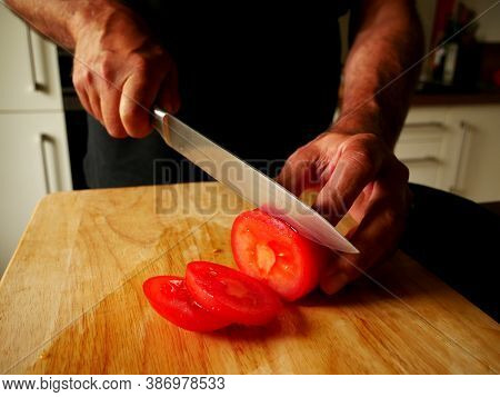 Man Cutting Tomatoes On A Wooden Board