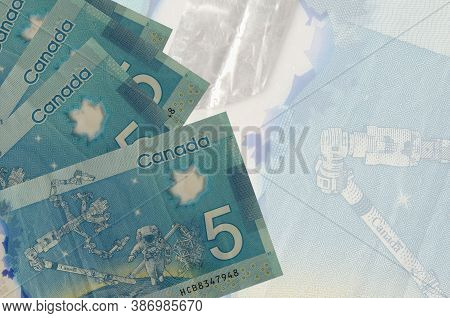 5 Canadian Dollars Bills Lies In Stack On Background Of Big Semi-transparent Banknote. Abstract Busi