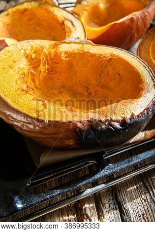 Close-up Of Halves Of Homemade Freshly Baked Bright Orange Pumpkins On Baking Sheet And On Oven Tray