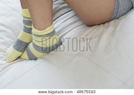 Sección baja de mujer que llevaba calcetines tumbado en la cama