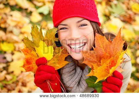 Mujer otoño sostiene caída deja en bosque sonriendo feliz y emocionado. Retrato de muchacha linda cerca