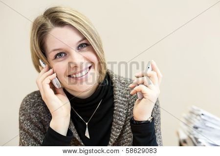 Beauty Happy Young Businesswoman Chatting On Two Smartphones In Office