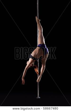 Flexible girl dancing on pilon, isolated black