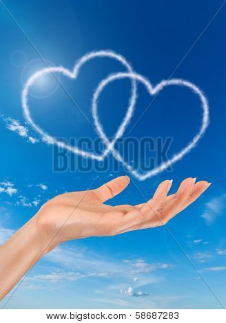 woman hand and heart shaped clouds