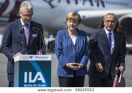 BERLIN, GERMANY - MAY 20, 2014: German Chancellor Angela Merkel (C) and Turkish Minister of transport Lutfi Elvan (R) open up the International aviation and space exhibition ILA.