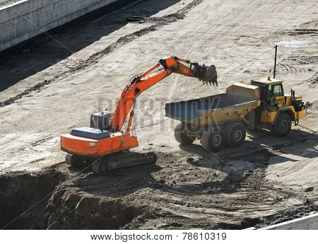 Excavator Loading Dumper Truck Tipper In Sandpit In Highway Construction Site