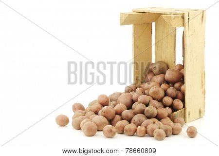 Cherry potatoes (small dutch potatoes) in a wooden crate on a white background