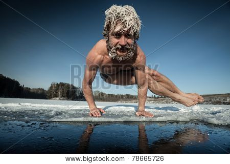 Man with frozen hair doing yoga exercise (parsva bakasana) on the ice