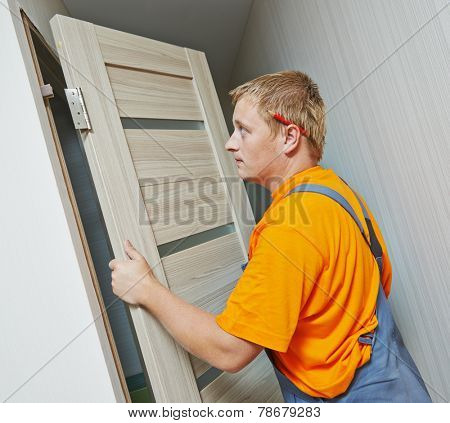 Male handyman carpenter at interior wood door installation