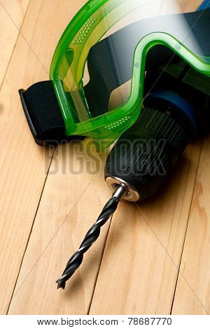 Handdrill And Goggles On Wooden Background