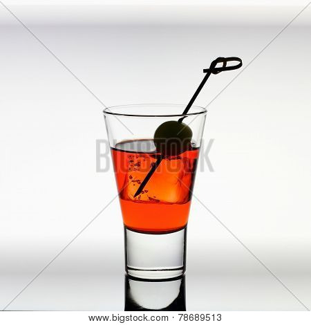 Short Drink Glass With Red Liquid, Olive, Ice Cubes
