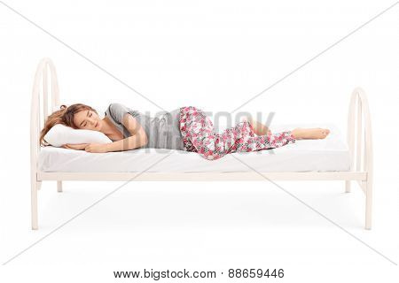 Beautiful brunette woman in pajamas sleeping in a comfortable bed isolated on white background