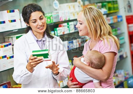 pharmacist chemist woman giving vitamins to mother with child in pharmacy drugstore