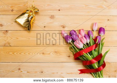 Tulips and gift on wooden texture