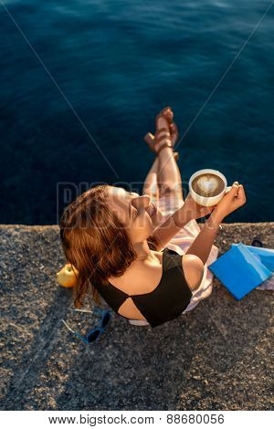 Young woman sitting on the pier at sunrise