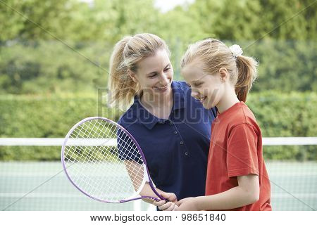 Female Tennis Coach Giving Lesson To Girl