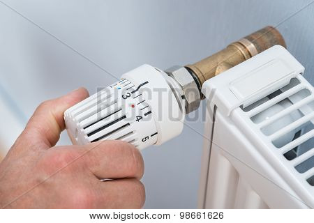 Person Adjusting Temperature Of Radiator Thermostat