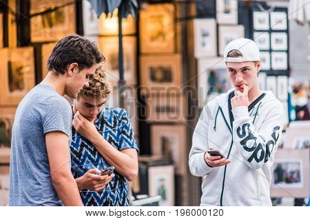 Montreal, Canada - May 27, 2017: Old Town Area With Young Boys Looking At Their Smartphones In Eveni