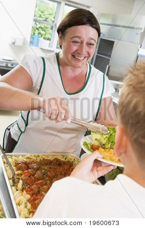 Lunch lady som serverar sallad till student
