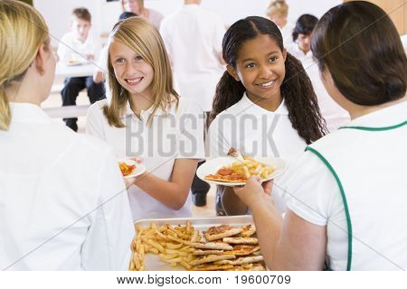 Studenter i cafeterian linje som serveras av lunch damer
