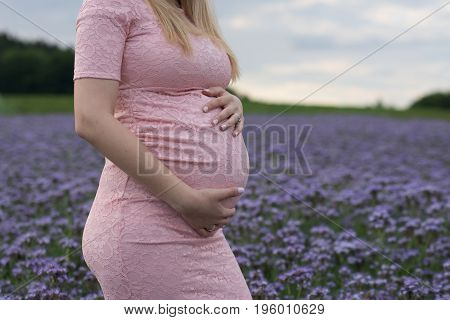 pregnant lady in pink dress on a field