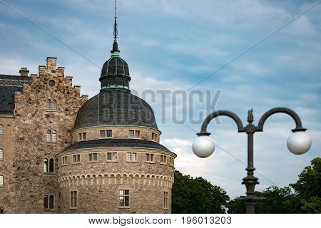 Old medieval castle in Orebro Sweden Scandinavia Europe. Landmark in foreground and blue cloudy sky in background. Architecture and travel.