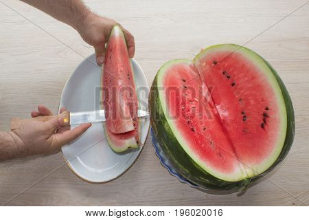 Men hand hold from on fresh watermelon cutting for eatin on table background. Male cutting a delicious sweet watermelon